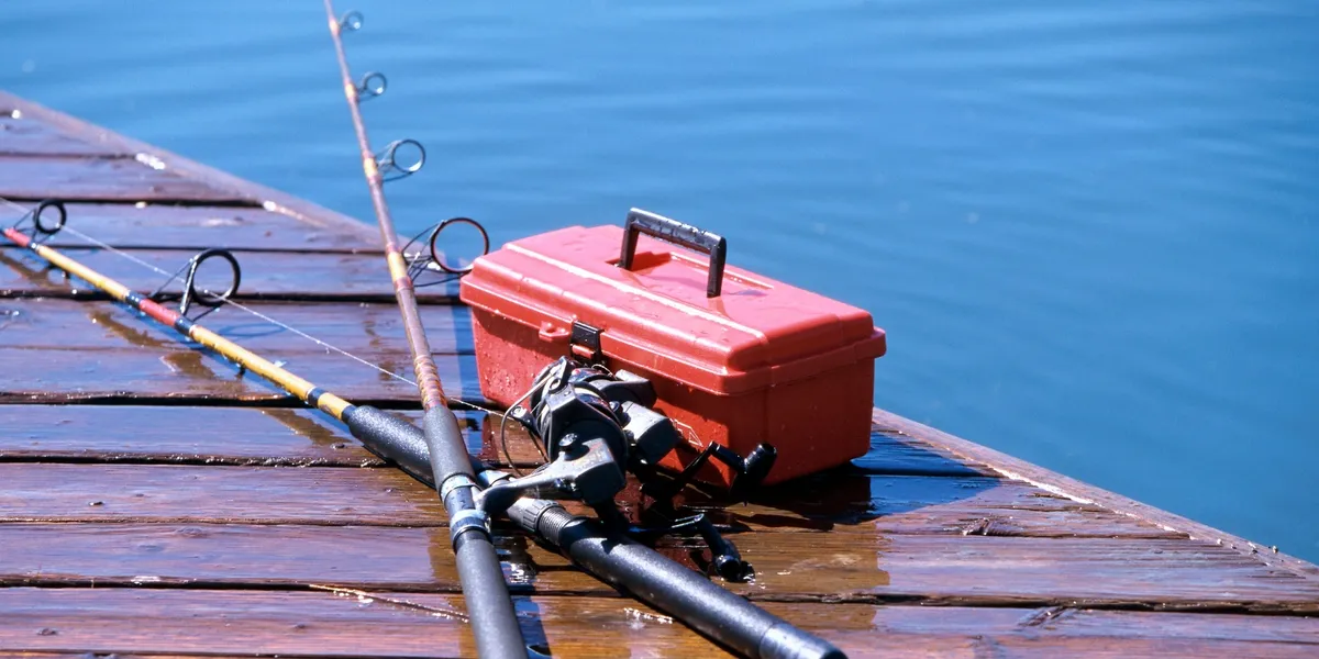 Photo of fishing rods and tackle box on a dock.